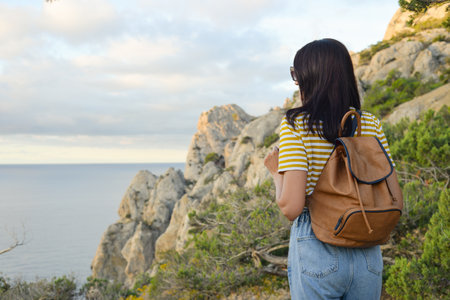 A female tourist with a backpack traveling through the Crimea village of Novy Svet. Girl on the edge...