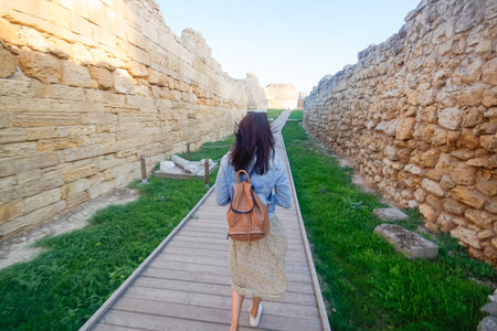 A woman tourist with a backpack walks and examines the ruins of an ancient city. Khersones, Sevastopol, Crimea.の写真素材