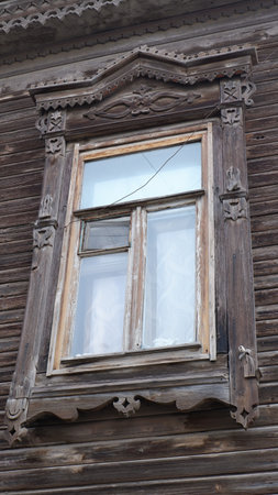 Old wooden windows with shutters on a wooden house with rustic carved designs, with intricate carvings on topの写真素材