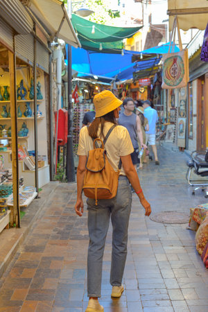 A young woman tourist with a backpack walks through the tourist market in Turkey in Antalya looking for a souvenir.の写真素材