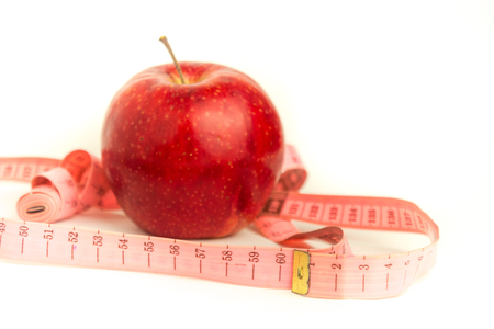 Bright red apple and pink measuring tape on a white backgroundの写真素材