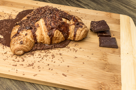 Croissant with hot chocolate on a wooden board and pieces of chocolateの写真素材