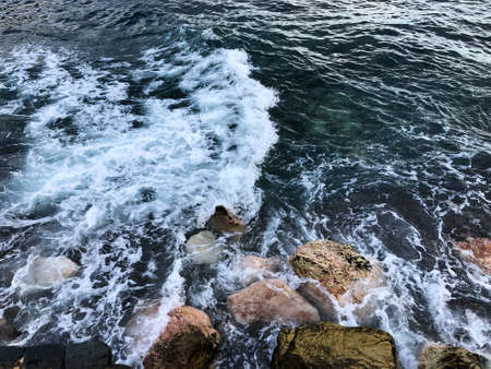 Waves break on rocks on the black seaの写真素材