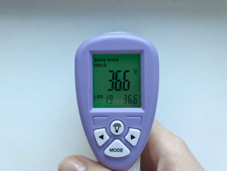 Electronic thermometer in hand. A medical instrument, an electronic digital thermometer, is used to measure a patient's temperature in a hospital. Close-up, in hand thermometer on white background.の写真素材