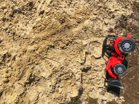 Sand in the sandbox. Children's toy, red tractor on the sand. Baby's toys outdoorの写真素材