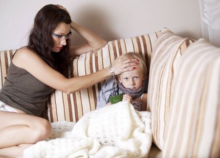mother touches hot forehead with my daughterの写真素材