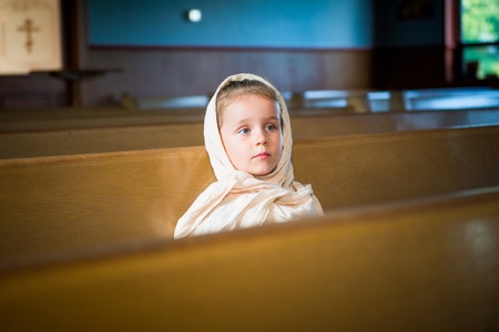 Portrait of the child  girl  sitting on the bench in the orthodox churchの写真素材
