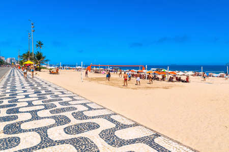 Ipanema beach with mosaic of sidewalk and people playing volleyball in Rio de Janeiro. Brazilの写真素材