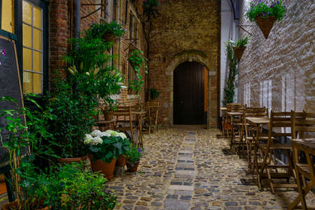 Old cozy narrow street with tables of restaurant in historic city center of Antwerpen (Antwerp), Belgium. Night cityscape of Antwerp. Architecture and landmark of Antwerpenの写真素材