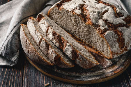 Homemade rye bread. Sliced rye bread in a round shape on a wooden background in a rustic style with...