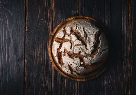 Homemade rye bread. Rye bread in a round shape on a wooden background in a rustic style. Top view.