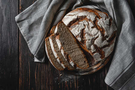 Homemade rye bread. Sliced rye bread in a round shape on a wooden background in a rustic style with towel. Top view.の写真素材