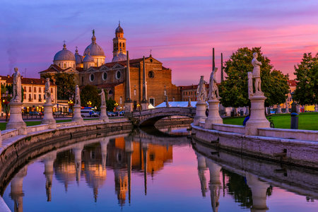View of canal with statues on square Prato della Valle and Basilica Santa Giustina in Padova (Padua), Veneto, Italy. Sunset cityscape of Padua.の写真素材