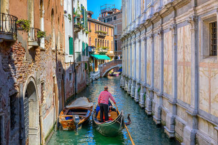 Narrow canal with gondola and bridge in Venice, Italy. Architecture and landmark of Venice. Cozy cityscape of Venice.の写真素材