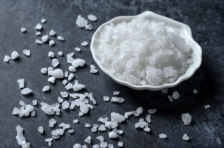 Sea salt in bowl on black background. Coarse salt.の写真素材