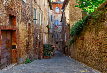 Medieval narrow street in Siena, Tuscany, Italy. Architecture and landmark of Siena. Cozy cityscape of Sienaの写真素材