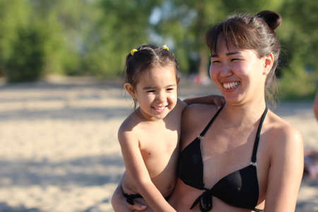 Beautiful asian girl hugging her baby and laughing happilyの写真素材