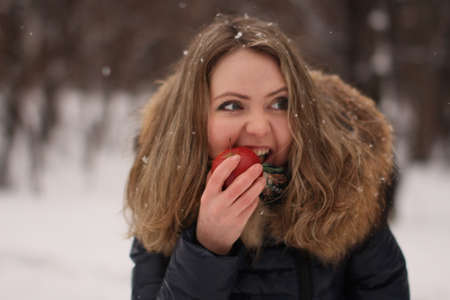 Beautiful happy girl with long curly hair with an apple in her handsの写真素材