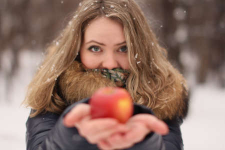 Beautiful happy girl with long curly hair with an apple in her handsの写真素材