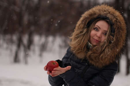 Beautiful happy girl with long curly hair with an apple in her handsの写真素材