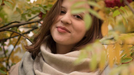 Portrait of an attractive caucasian woman smiling against a background of autumn foliageの写真素材