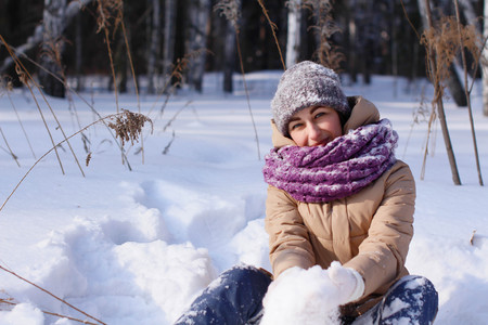 A contented Caucasian woman walks in a winter park. Young woman against a snow-covered park on a sunny dayの写真素材