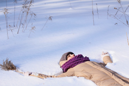 A contented Caucasian woman walks in a winter park. Young woman against a snow-covered park on a sunny dayの写真素材