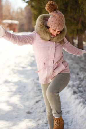 A contented Caucasian woman walks in a winter park. Young woman against a snow-covered park on a sunny dayの写真素材