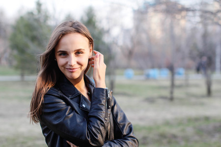 cute smiling young woman looking at you. Portrait of a beautiful girl with long hair in a city park in springの写真素材