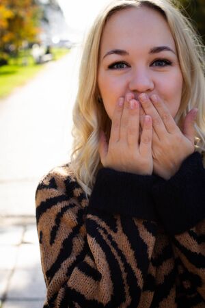 Portrait of a beautiful young woman enjoying autumn in the park. Attractive blonde in autumn park on...