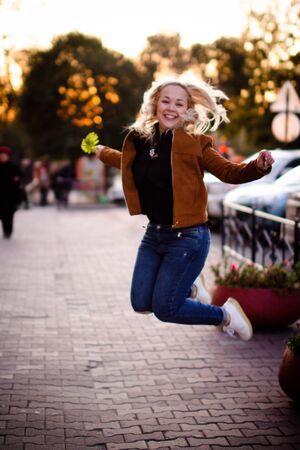 Portrait of a beautiful young woman enjoying autumn in the park. Attractive blonde in autumn park on a background of trees in yellow foliageの写真素材