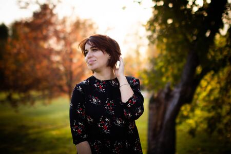 Young pretty woman on autumn park background with evening light