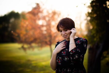 Young pretty woman on autumn park background with evening lightの写真素材