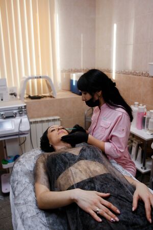 Russia, Novosibirsk, January 5, 2020. Woman lies with her eyes closed during the procedure in the beauty parlorのeditorial素材
