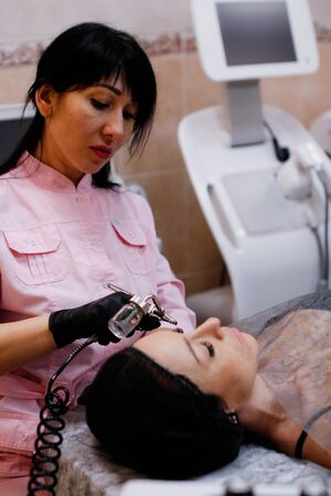 Russia, Novosibirsk, January 5, 2020. Woman lies with her eyes closed during the procedure in the beauty parlorのeditorial素材