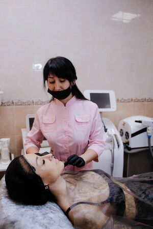 Russia, Novosibirsk, January 5, 2020. Woman lies with her eyes closed during the procedure in the beauty parlorのeditorial素材