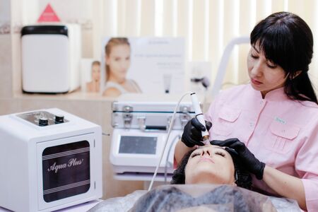 Russia, Novosibirsk, January 5, 2020. Woman lies with her eyes closed during the procedure in the beauty parlorのeditorial素材