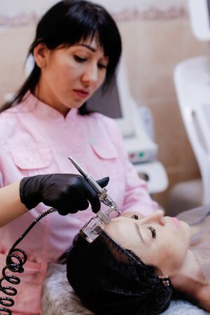 Russia, Novosibirsk, January 5, 2020. Woman lies with her eyes closed during the procedure in the beauty parlorのeditorial素材