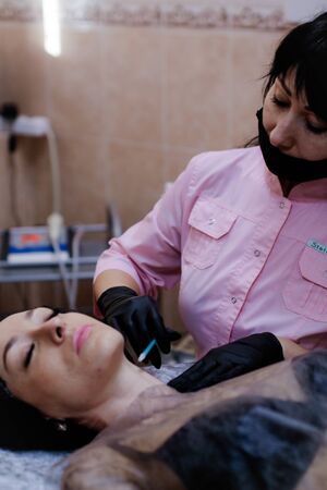 Russia, Novosibirsk, January 5, 2020. Woman lies with her eyes closed during the procedure in the beauty parlorのeditorial素材