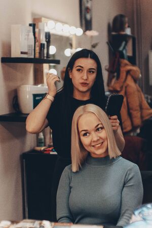 Beautiful young woman hairdresser giving new haircut to female client at salonの写真素材