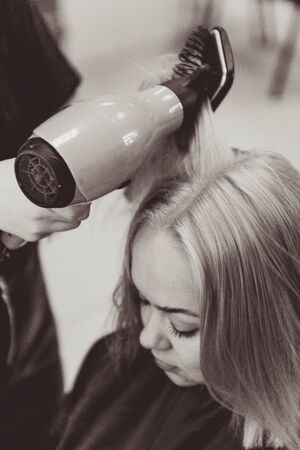 Beautiful young woman hairdresser giving new haircut to female client at salon.