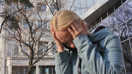Woman suffering from headache on the street.