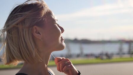 Portrait of a happy young woman in the light of the morning sun. A woman is enjoying music on...