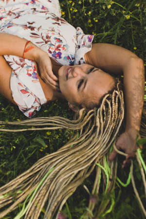 Attractive young smiling woman lying on green grass in parkの写真素材