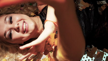 Crazy New Years Eve. A beautiful blonde lies on the floor of golden confetti.の写真素材