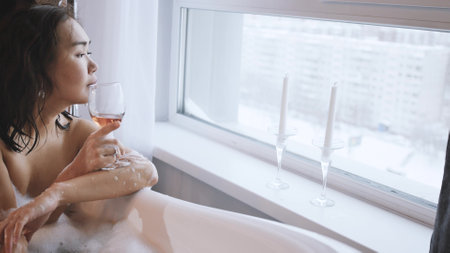 Relaxed asian woman drinking champagne in a luxurious bath