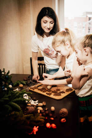 two cute sisters and mom sculpt and decorate Christmas gingerbreadの写真素材