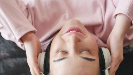 Attractive woman listening to music using headphones on bed at home.の写真素材