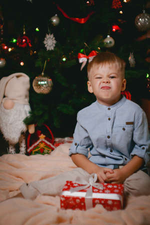 little boy rejoices at his present near the christmas tree. close-up. Slow motionの写真素材