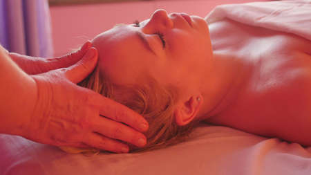 Young woman enjoying head massage in spa salonの写真素材